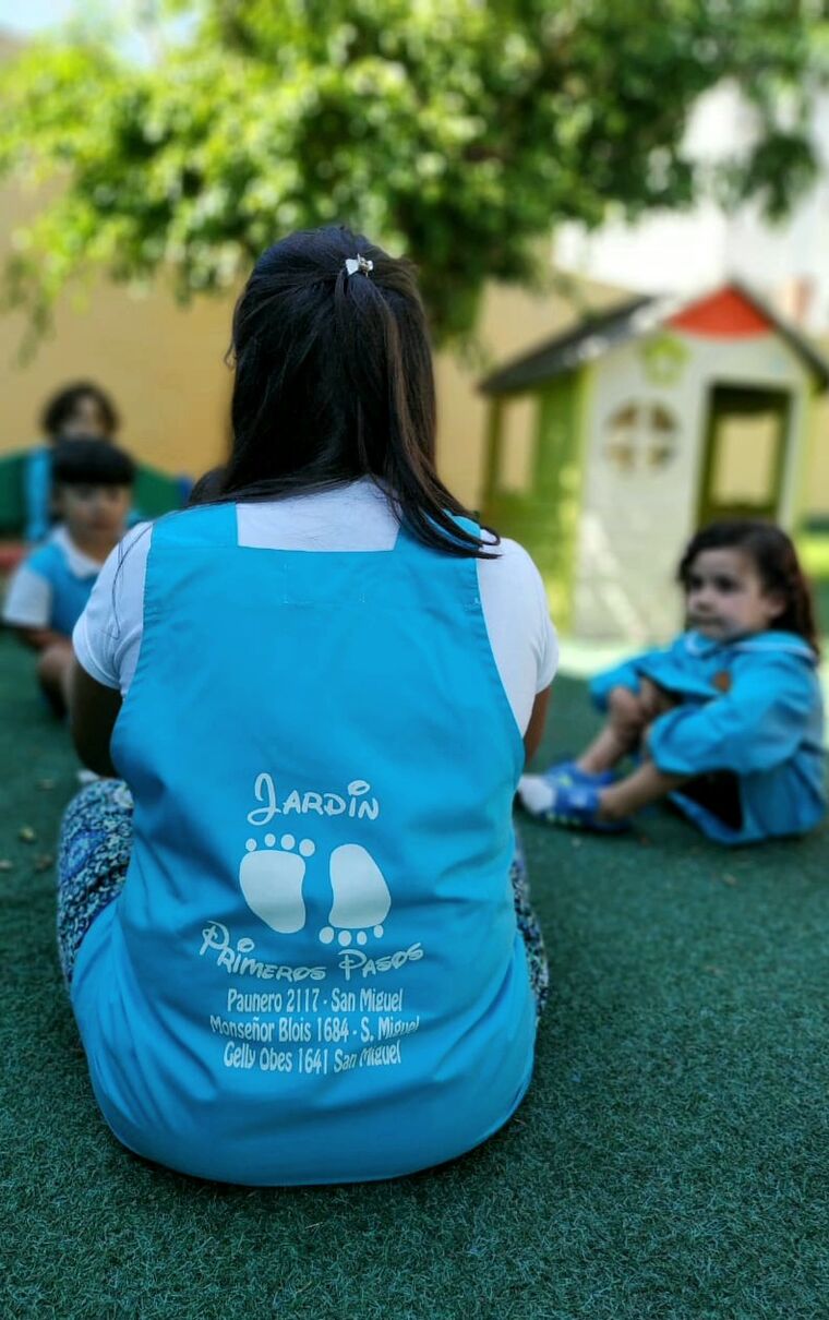 Docente acompañando a niños en el patio del jardín